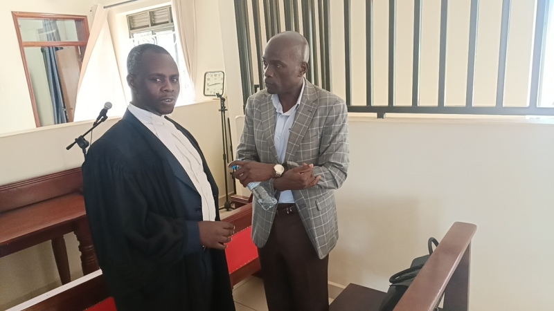 Muhangi George lawyer for Maj Mark Wanyama discussing with him inside the court.